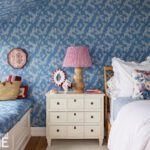 Guest bedroom with patterned blue and white wallpaper.
