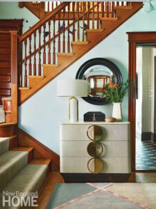 Entry way of early 1900s home with natural wood moldings and staircase.