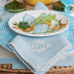 Light blue table setting featuring monogrammed linen napkins