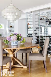 Round dining table and chairs with large wine rack in the background.