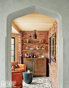 Cozy garden room with brick lined walls with a bronze bar and floating shelves.