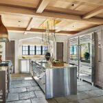 Kitchen with stainless steel cabinetry, stone floors, and rustic wood.