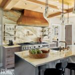 Kitchen with stainless steel cabinets, bronze range hood, and marble countertops.