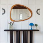 Black contemporary console with a midcentury modern mirror.