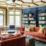Library with a drawn plaster ceiling, blue walls, and salmon colored couches.