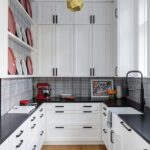 White butlers pantry with a black countertop and cabinet handles.