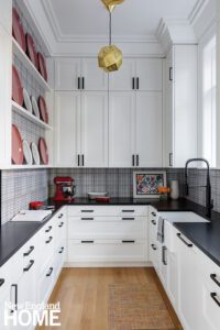 White butlers pantry with a black countertop and cabinet handles.