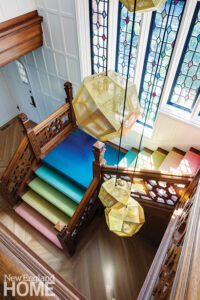 Stairway of a Tudor home with stained glass windows and an ombre stair runner