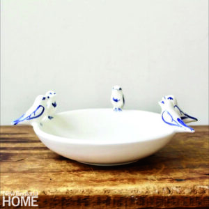 a white bowl with three blue and white ceramic birds on the rim