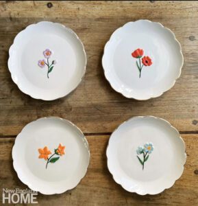 Four white plates painted with wildflowers
