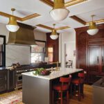Old world style kitchen with coffered ceilings and a large brass range hood.