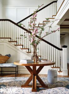Entryway with a round table and vase of blooms.
