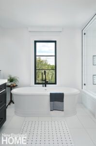 Large white soaking tub in front of a window.