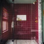 Walk in shower with red tile and marble floor