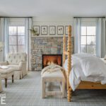 Bedroom with a stone fireplace and light oak bed
