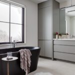 Primary bedroom with gray cabinetry and black bath tub