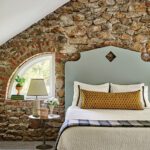 Upholstered headboard in front of a rustic stone wall