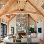 Large living room with a reclaimed stone fireplace and white oak cathedral ceiling