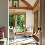 View of a sunny guest room with large windows and wood beams