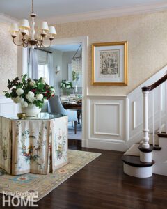 Entryway to a home with paneled wainscoting and a round skirted table