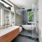 Contemporary bathroom with a floating oak vanity and white soaking tub