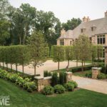 Elegant stone home with traditional landscaping with pleached lindens