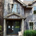 Exterior entrance to a home with dark green doors and shingle siding