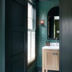 Powder room with dark green walls and a light wood vanity