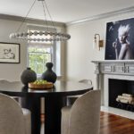 Dining room with a round table, modern light fixture and bold art.