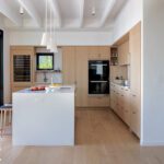Kitchen with white oak cabinetry and a white ceiling with exposed painted beams