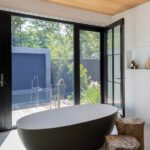 Bathroom with a large soaking tub in front of a wall of windows