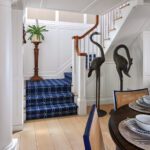 Entryway with stairs that have a blue stairrunner and large bird sculptures