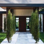 Front entrance to a midcentury home with a row of junipers
