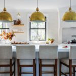 Kitchen island with an island with a waterfall countertop and large brass pendant lights.