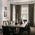 Dining room with white walls, dark furniture, and silk drapery