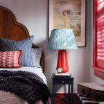 Guest room with an antique bed, vintage poster and red lamp.