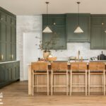 Kitchen with sage green cabinets, wood island and leather counter stools
