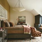 Primary bedroom with layered textiles, grasscloth and large pendant over the bed.
