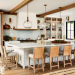 Contemporary kitchen with a large kitchen island, glass globe pendants and rattan chairs.