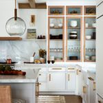 White kitchen cabinetry with wood accents and brass hardware