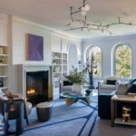 Living room with contemporary furnishings, limestone fireplace, and arched windows
