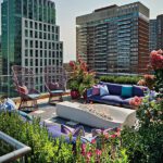 Colorful rooftop lounge showcasing comfortable seating, lush greenery, and panoramic city views in Boston.