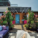 Dramatic rooftop terrace with a pergola, vibrant floral arrangements, and cozy seating in a cityscape setting.