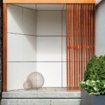 Elegant front entry featuring natural wood, stone elements, and lush greenery for a harmonious first impression.