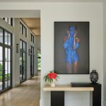 Minimalist hallway in a Greenwich modern farmhouse featuring light wood floors, neutral decor, and bold contemporary artwork in blue tones.