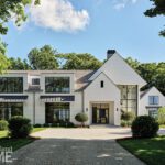 Expansive front view of a white shingle-style Greenwich home with large black-framed windows, pitched roofs, and manicured landscaping.