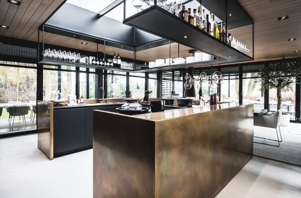 Contemporary kitchen with VeroMetal bronze island, black cabinetry, and a skylight ceiling showcasing a sleek, open-concept design.