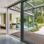 Contemporary U-shaped home with floor-to-ceiling windows surrounding a courtyard and outdoor dining patio.