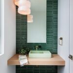 Stylish powder room with glossy green tile backsplash, floating vanity, and pendant lighting.