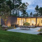 Open-concept modern home with sliding glass doors opening to a landscaped courtyard and wooded backyard.